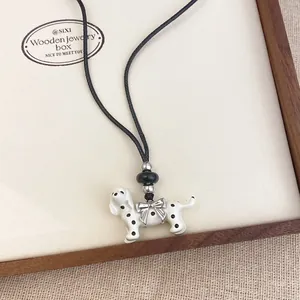 Detailed macro view of dalmatian puppy pendant necklace with bow on a wooden display tray