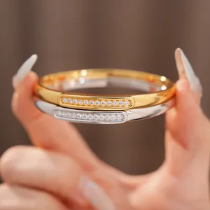 Detailed view of 18K gold-plated oval bangles with shimmering zircon inlay detail.