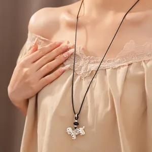 Detail showing a white polka dot Dalmatian puppy pendant with a bow on a black cord