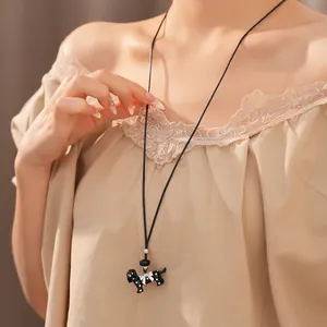Detailed macro shot of a cute black polka dot dog necklace with a black leather cord.
