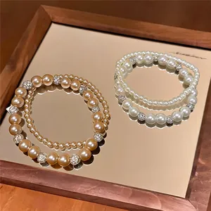 Detailansicht eleganter zweilagiger Perlenarmbänder mit funkelnden Kristall-Zierelementen.
