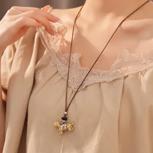 Detail shot of a spotted dog pendant necklace with a leather cord and silver bow.