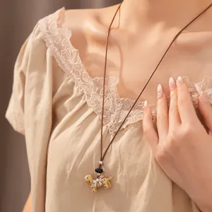 Close-up of a cute spotted puppy pendant necklace worn with a lace top