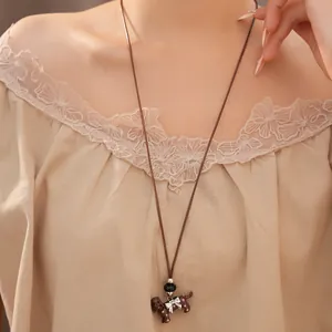 Close-up of a long brown cord necklace with a polka dot dachshund dog pendant
