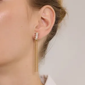 Gros plan de boucles d'oreilles dorées en acier avec zircons marquises et franges.