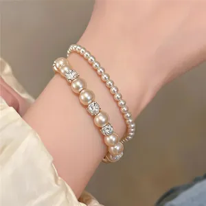 Detailansicht von geschichteten Perlenarmbändern mit glitzernden Strass-Abstandshaltern am Handgelenk