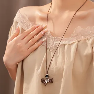 Close-up detail of a brown leather cord necklace with a cute polka dot dog pendant