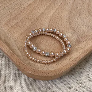 Elegantem champagnerfarbenem Perlenarmband-Set mit funkelnden Kristall-Zwischenteilen.
