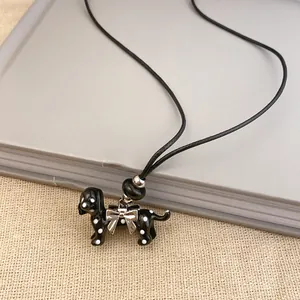 Macro view of a cute polka dot dog pendant necklace featuring a silver bow charm