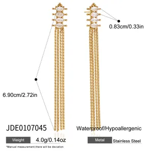 Détail de boucles d'oreilles en acier inoxydable doré avec pompons et zircon marquise