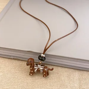 Detail close-up of a cute brown enamel dachshund dog pendant necklace with a silver bow