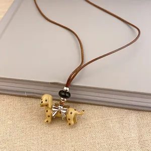 Close-up of a spotted dog pendant necklace with a leather cord and silver bow.