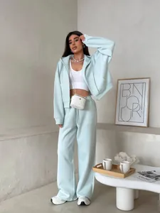 Woman in mint blue long sleeve zip hoodie and sweatpants set in minimalist room