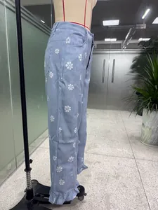 Close-up of light blue wide-leg pants with daisy floral print and ruffled hem.