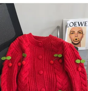 Red chunky knit cardigan with cute cherry pom-pom details and cable knit patterns