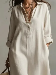 Close-up of a beige linen cotton shirt dress with relaxed fit and rolled-up sleeves.