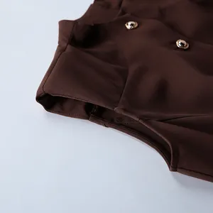 Close-up of French retro brown sleeveless dress showing elegant gold button detail.