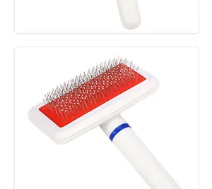 Detail of a pet slicker brush with fine metal bristles and red cushion background.