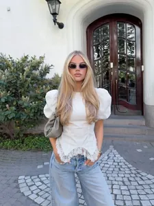 Elegante witte pofmouw blouse met kant in een streetstyle lifestyle omgeving geplaatst
