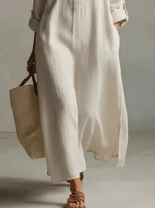 Detail shot of a beige cotton linen long shirt dress showing fabric texture and side slit