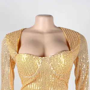 Close-up detail of shimmering gold sequins on a sexy long-sleeved nightclub dress.