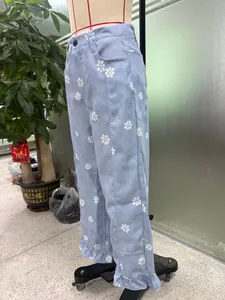 Close-up detail of light blue wide-leg floral print jeans featuring a stylish ruffle hem