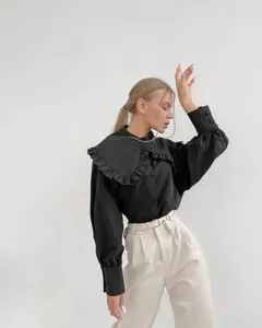 Detail shot of black French style blouse featuring a large ruffled Peter Pan collar