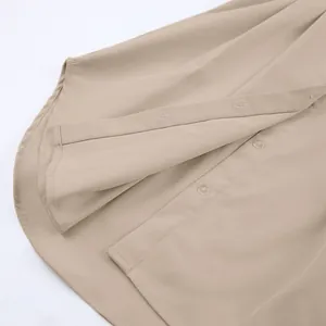 Detailopname van de ronde zoom en knopen van een beige Franse overhemdjurk.