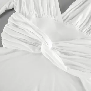 Vista detallada del elegante nudo delantero en este top de modal blanco con cuello en V