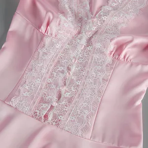 Close-up of white lace trim and pink buttons on a soft satin French style dress