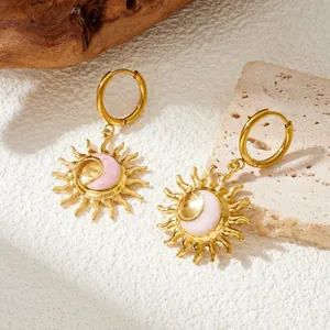 Makroansicht von vergoldeten Vintage-Sonnenohrringen mit rosa Emaille-Monddetails.