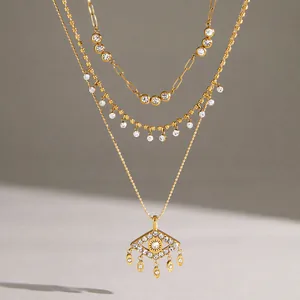 Primer plano de un collar de capas de acero inoxidable chapado en oro con ojo turco de cristal