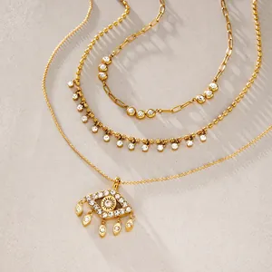 Detalle de collar de triple capa dorado en acero con colgante de ojo de la suerte