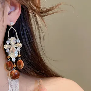 Détail de boucles d'oreilles de style palais vintage avec zircons et perles couleur ambre