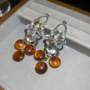 Gros plan de boucles d'oreilles rétro en zircon avec perles d'ambre dans un écrin à bijoux.