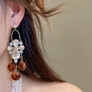 Gros plan sur des boucles d'oreilles pendantes de style vintage avec pierres ambrées et oxydes.