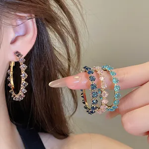 Detailed close-up shot of sparkling multi-color zircon hoop earrings worn by a model