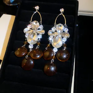 Vue détaillée de boucles d'oreilles rétro en zircon ambre et or sur velours noir.