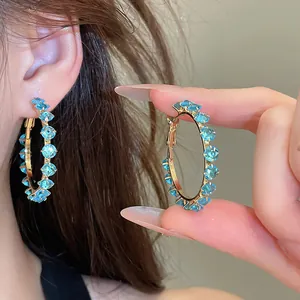 Close-up view of sparkling blue zircon hoop earrings with a premium gold finish.
