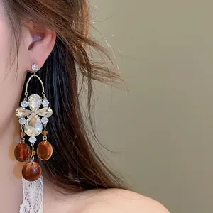 Gros plan de boucles d'oreilles vintage en zircon avec breloques ambre sur un modèle.