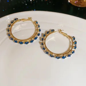 Detailed view of gold hoop earrings featuring elegant dark blue cubic zirconia stones.