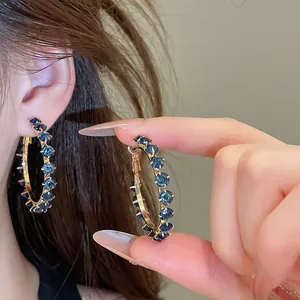 Detailed view of elegant silver needle hoop earrings with sparkling blue zircon stones