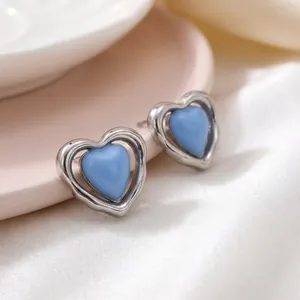 Primer plano de elegantes pendientes de corazón de resina azul con marco de plata hueca