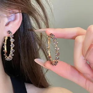 Detailed view of elegant purple zircon gold-plated hoop earrings shown on model's ear