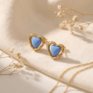 Detalle de pendientes de corazón en esmalte azul con marco de acero dorado