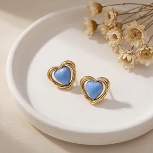 Detalle de pendientes de corazón en esmalte azul con marco de acero inoxidable dorado