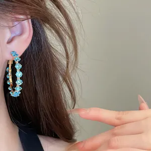 Detailed close-up of circular hoop earrings set with sparkling sky blue zirconia stones