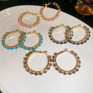 Selection of colorful zirconia hoop earrings in various shades displayed on a white plate