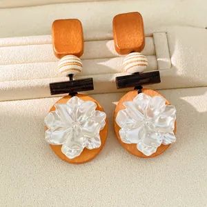 Primer plano de pendientes vintage con elementos de madera y flores de resina blanca