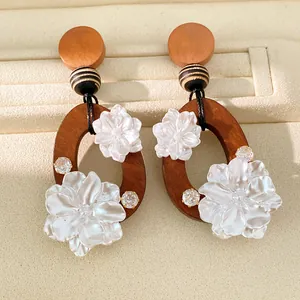 Detalle de pendientes hechos a mano de madera y flores de resina con toques de circón.